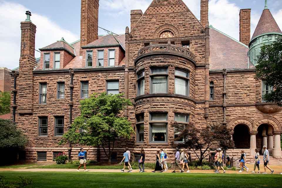 A tour of prospective students passes in front of Cupples House on a sunny day